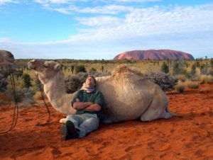 man leans on camel in the desert